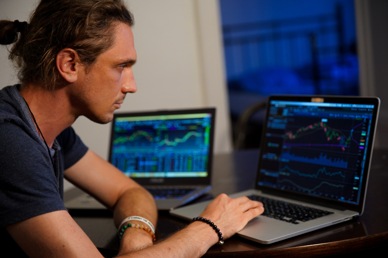 man sitting viewing stock market information on a laptop