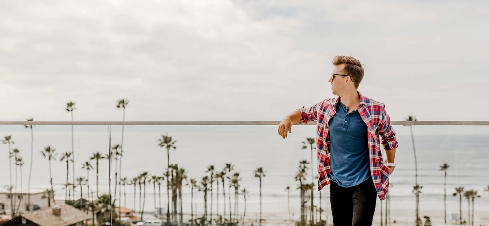 man standing against balcony with ocean view