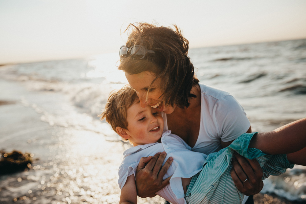 mother holding child smiling at the beach