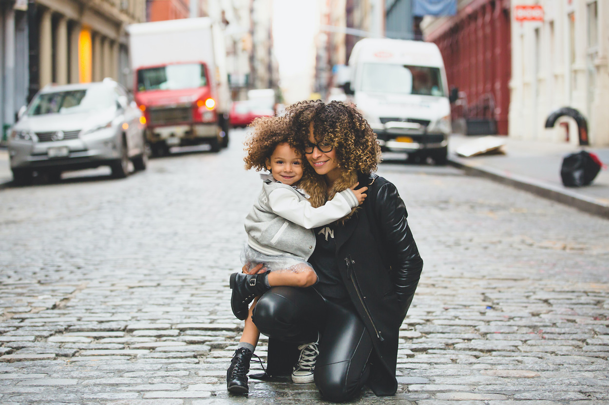 woman carrying a baby by the street during the day